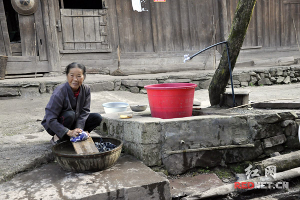 村里通了自来水后，六十多岁的鲁冬翠可以在自家门口洗衣服了。