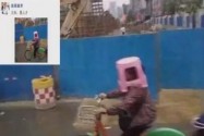 [视频]大妈骑车未带雨具 板凳套头当“雨伞”